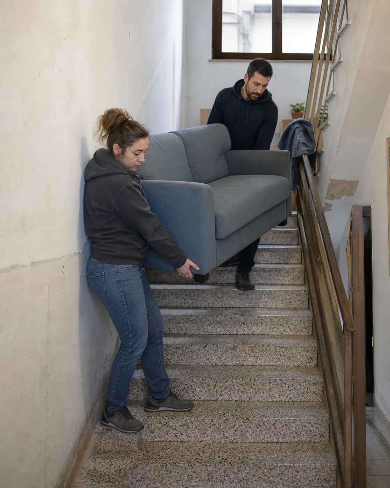 Due persone trasportano un divano sulle scale durante un piccolo trasloco a Padova