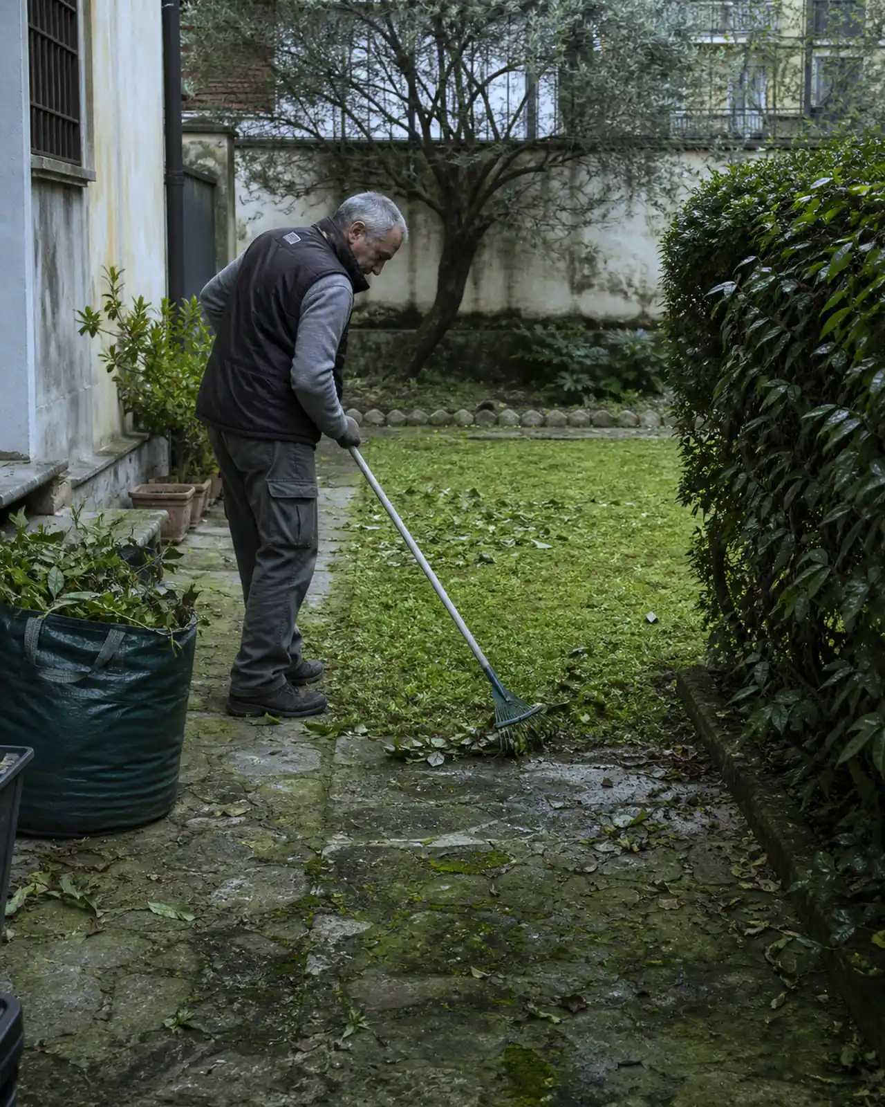 Giardiniere raccoglie foglie e ramaglie dopo il lavoro in un giardino a Padova